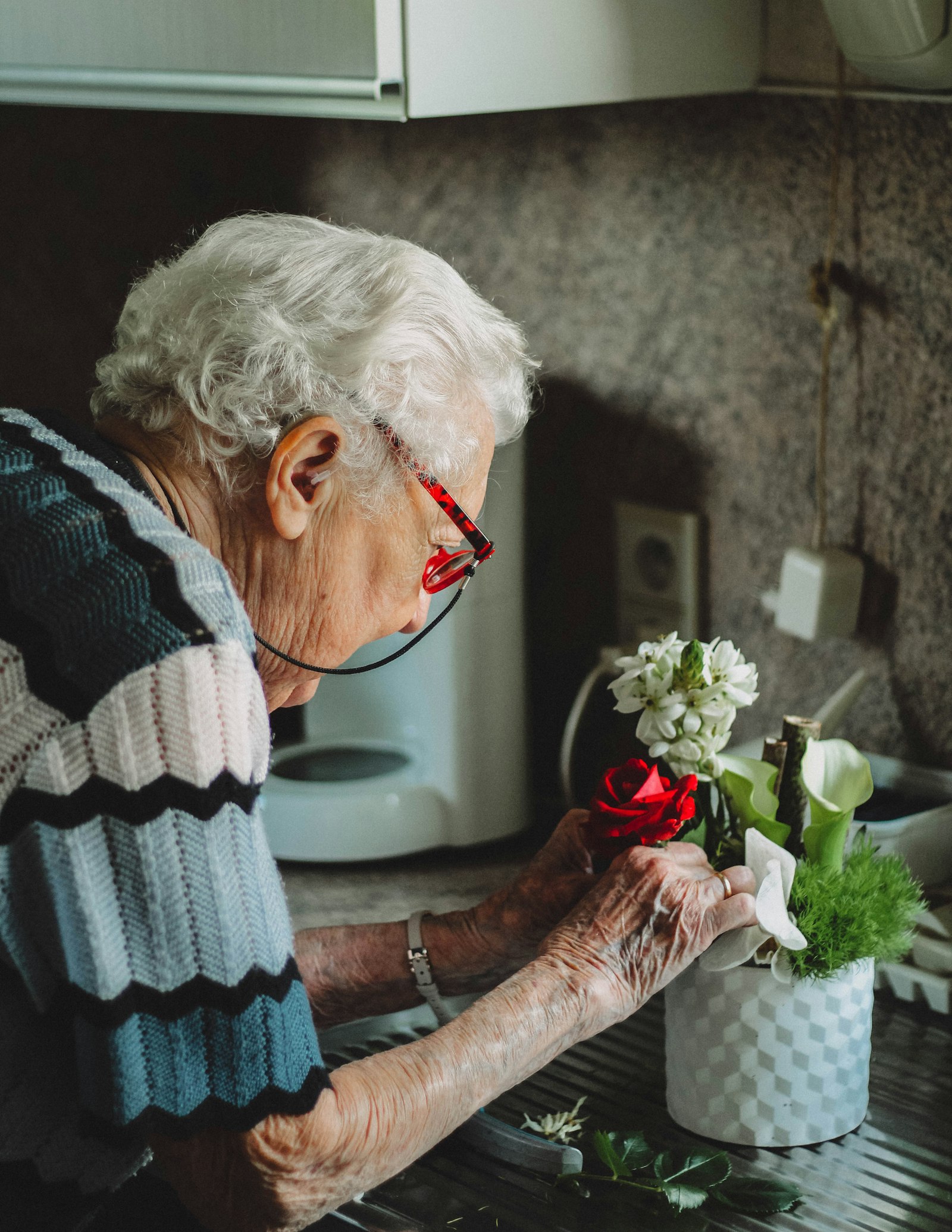 An elderly woman arranging fresh flowers to make her new place feel like home